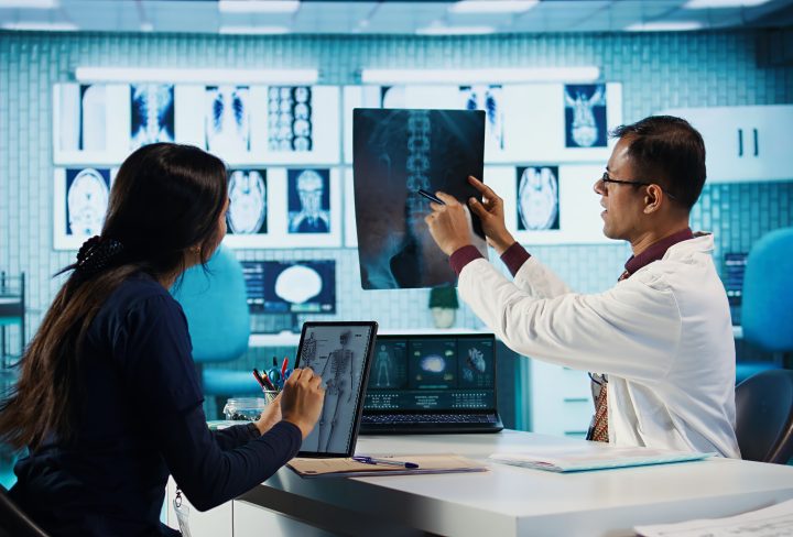 Professional doctor and patient engage in a medical check up for a scan interpretation of x ray and MRI results. General practitioner emphasizing healthcare practices and medical research. Camera B.